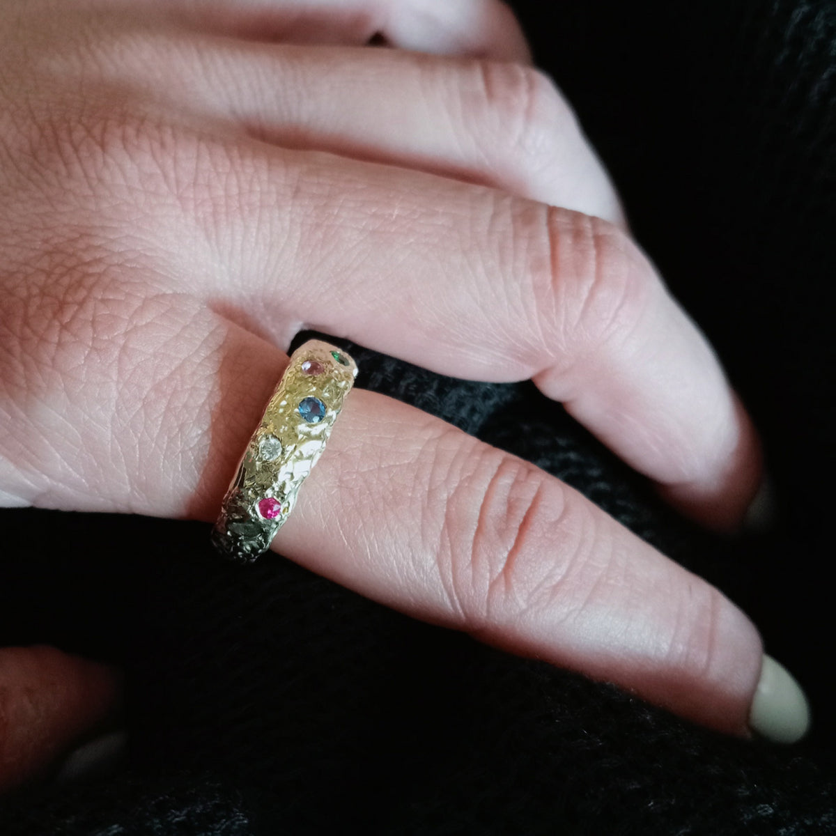 Anillo Casiopea de oro de 18 k con gemas de colores, puesto en la mano