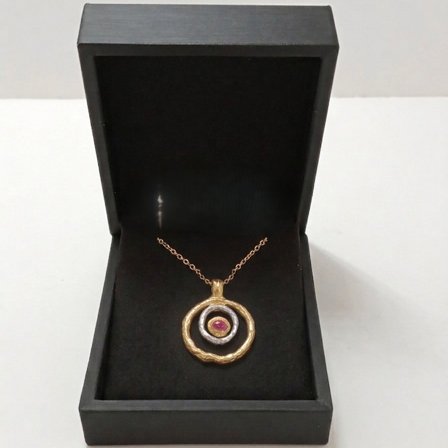 Colgante de plata y oro vermeil con rubí en bruto presentado en caja de joyería negra