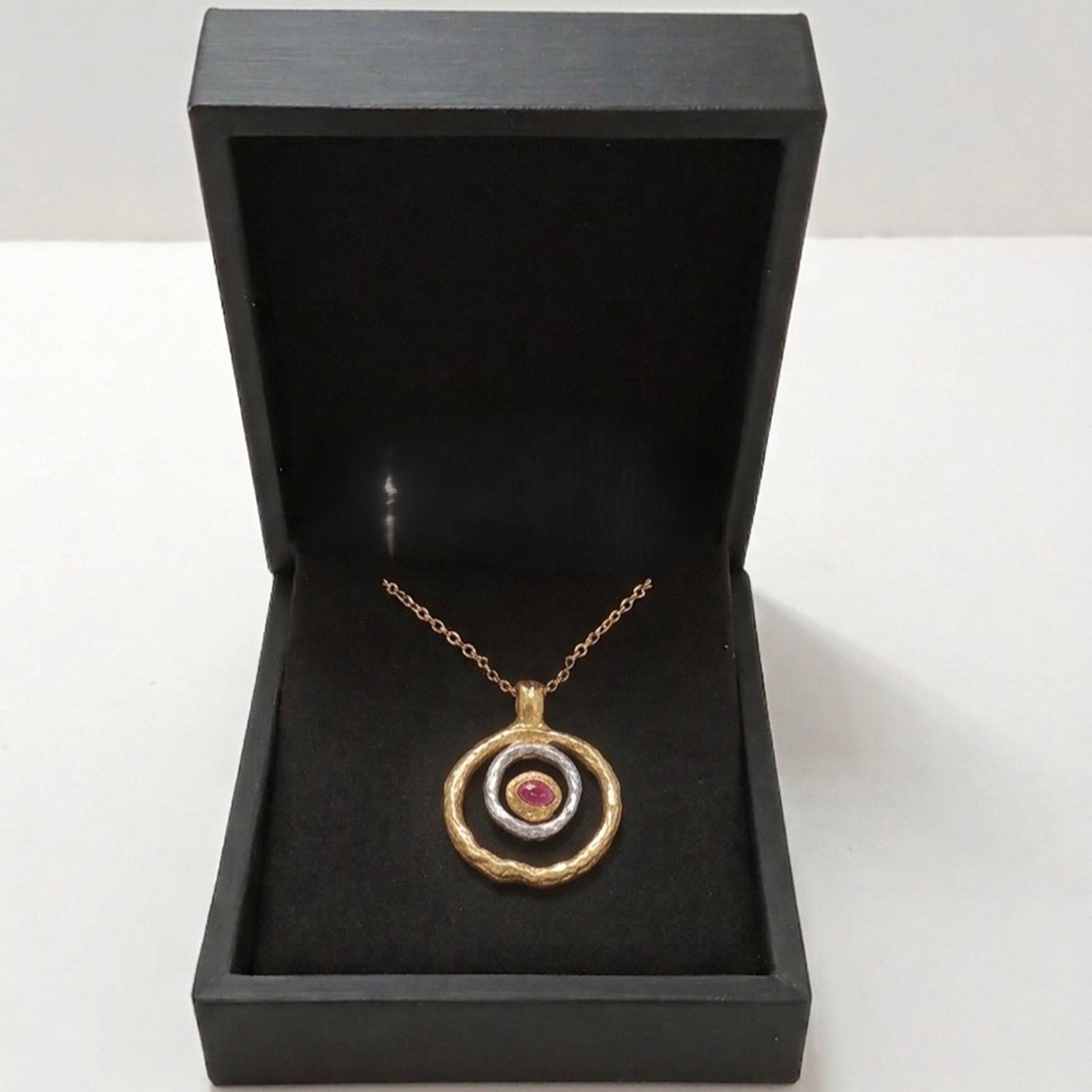Colgante de plata y oro vermeil con rubí en bruto presentado en caja de joyería negra