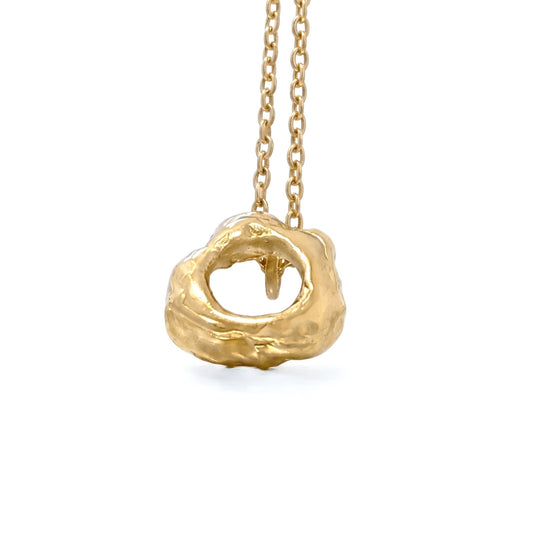 Colgante ovalado orgánico de oro vermeil con textura rugosa, suspendido de una cadena de eslabones finos sobre un fondo blanco puro.