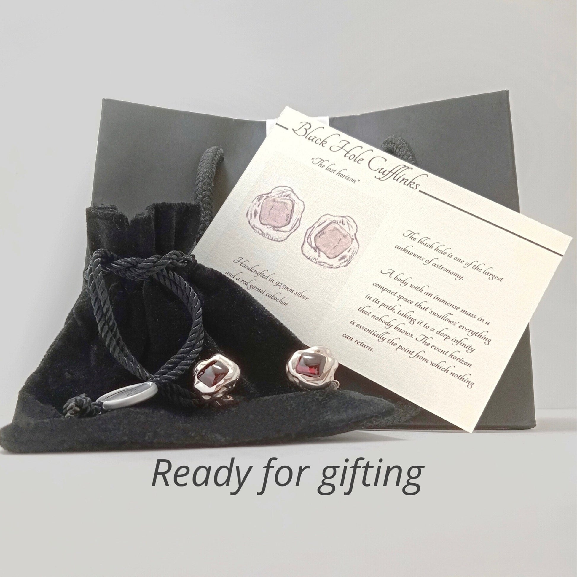 Packaging de regalo con gemelos, bolsa de terciopelo negra y tarjeta descriptiva "Black Hole Cufflinks".