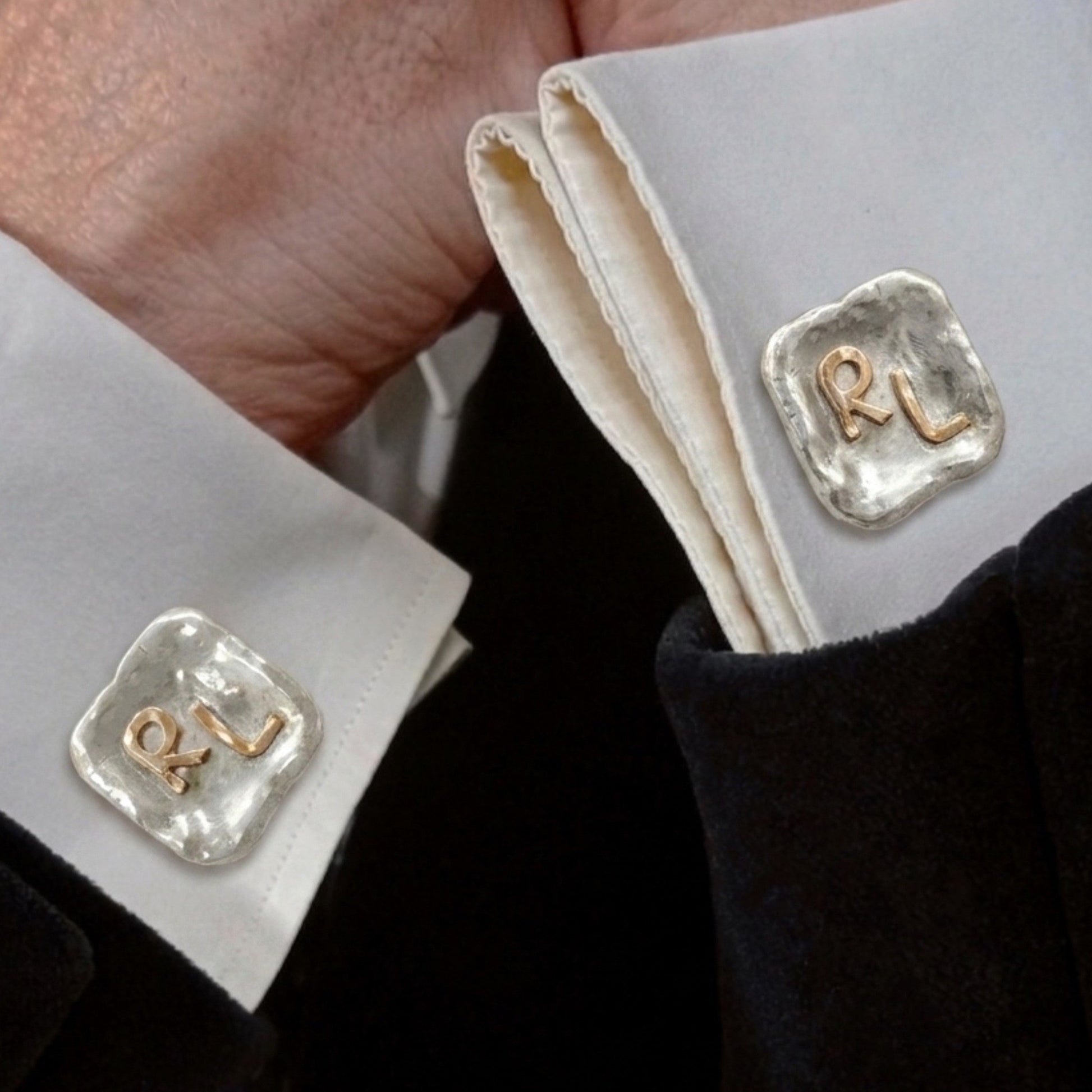 Gemelos de plata personalizados con iniciales RL en oro de 18K colocados en los puños de una camisa blanca. 