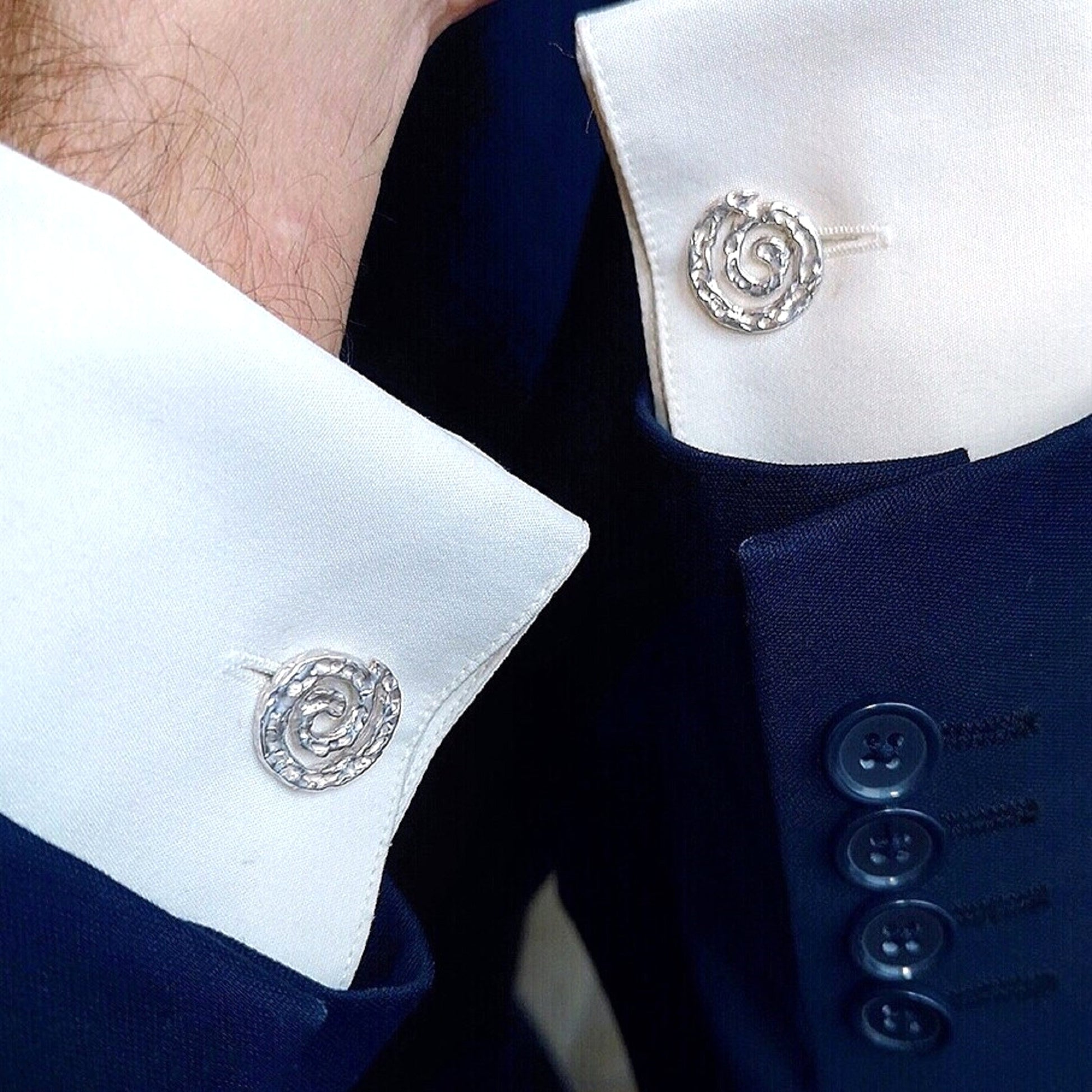 Gemelos de plata 925 con diseño de galaxia espiral puestos en el puño de una camisa blanca de hombre.