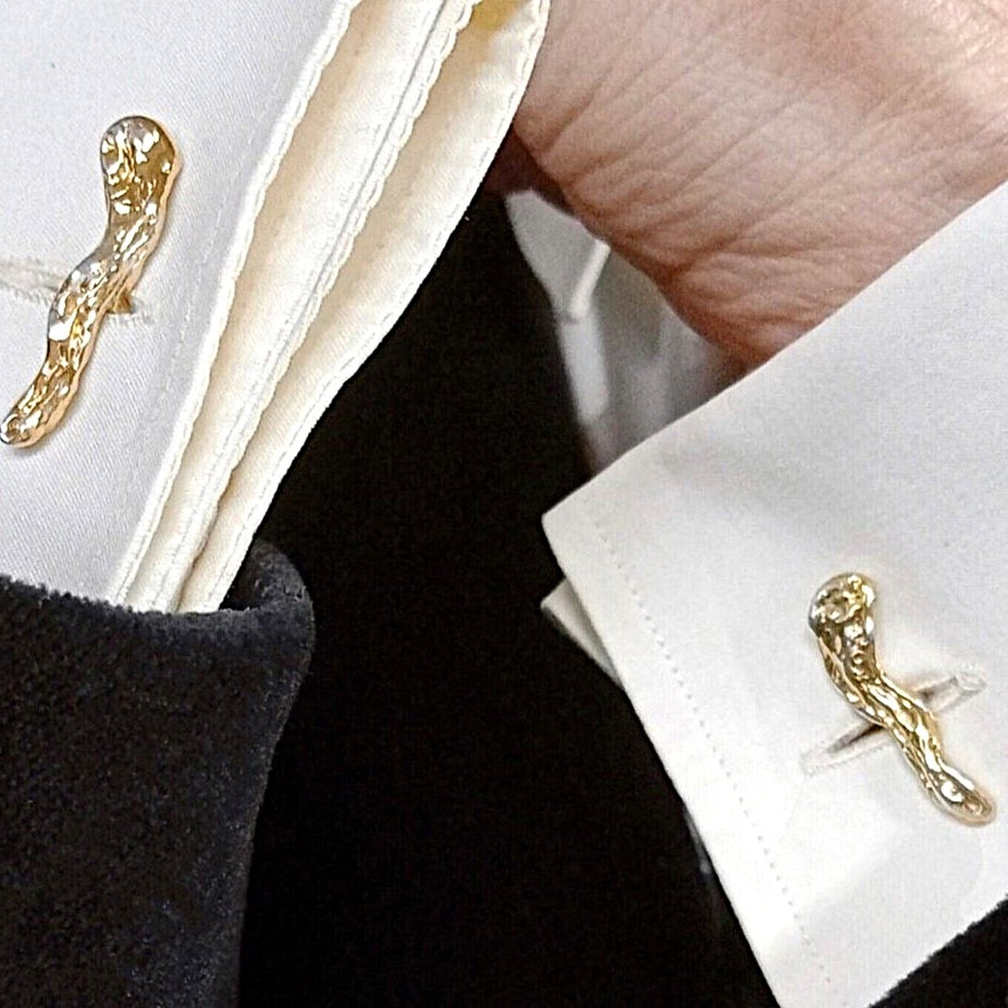 Gemelos de diseño orgánico en plata y oro vermeil puestos en puño de camisa blanca con chaqueta negra.